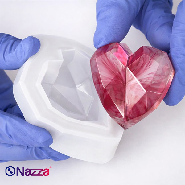 Molde de silicona con forma de corazón junto a una pieza de resina epoxi ya desmoldada.